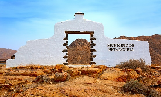 Puerta de piedra blanca con cartel de Municipio de Bentacuria